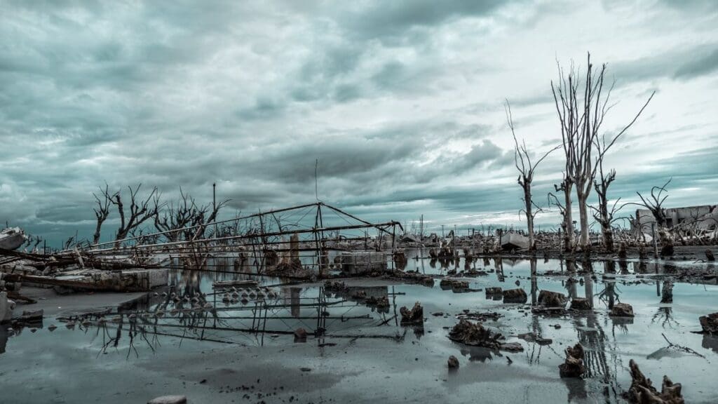 Landscape of building ruins and bare trees in the water under a cloudy sky on a gloomy day - Climate Change