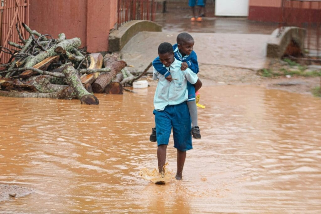 Image: Man in Blue Skirt and Blue Shorts Carrying a Boy in Blue Jacket while Walking on Water (s. El Niño)
