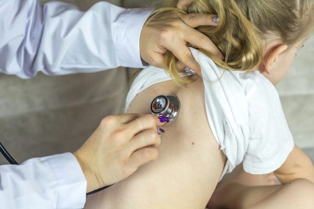 Image: a doctor examining a child with a stethoscope