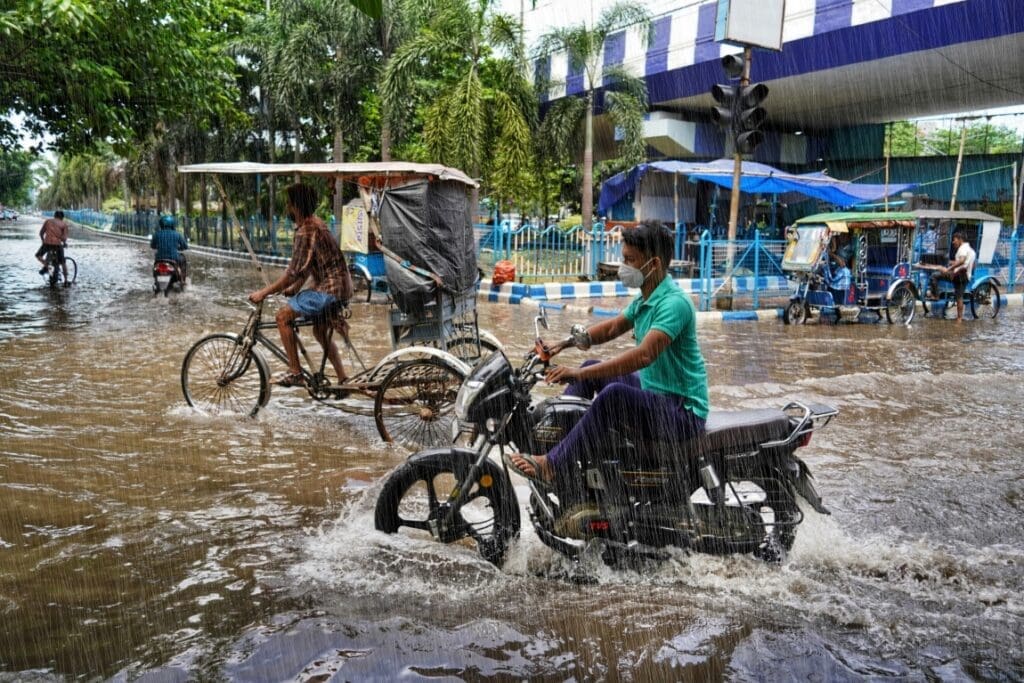 Why Indian cities flood during monsoon rains Image: people riding bicycles through a flooded street