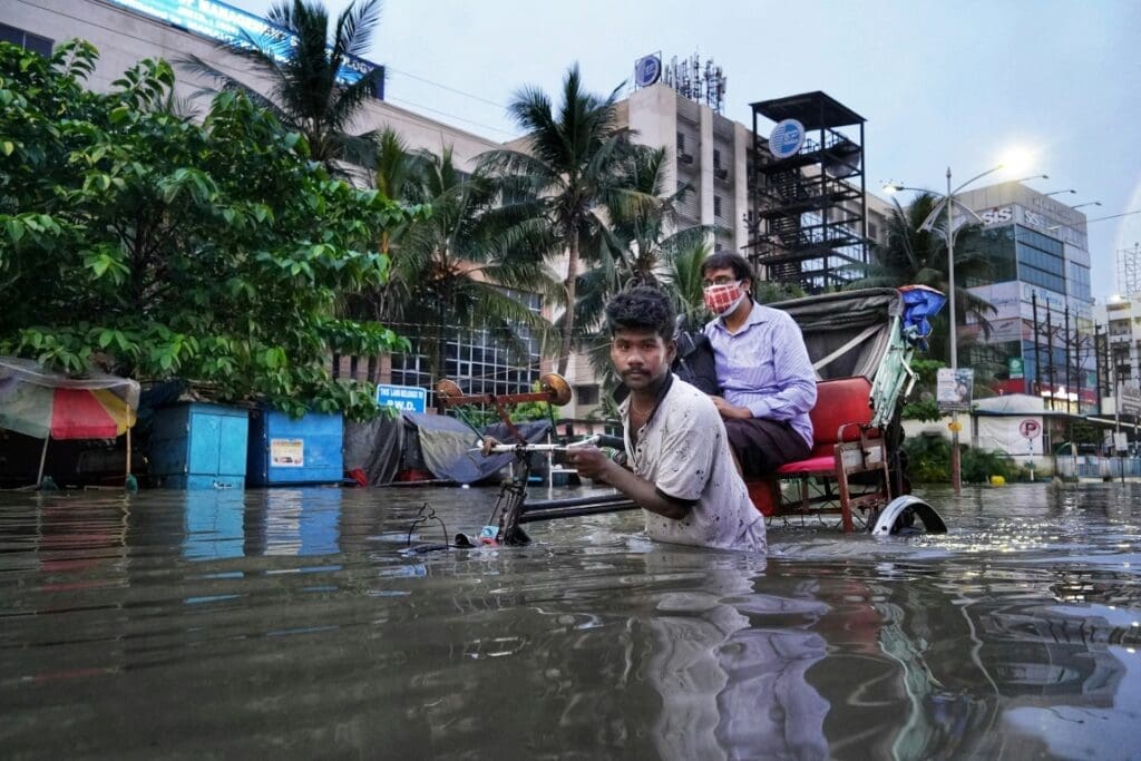 Climate change may worsen flooding in Mumbai and Chennai Image: a couple of men in a flooded street