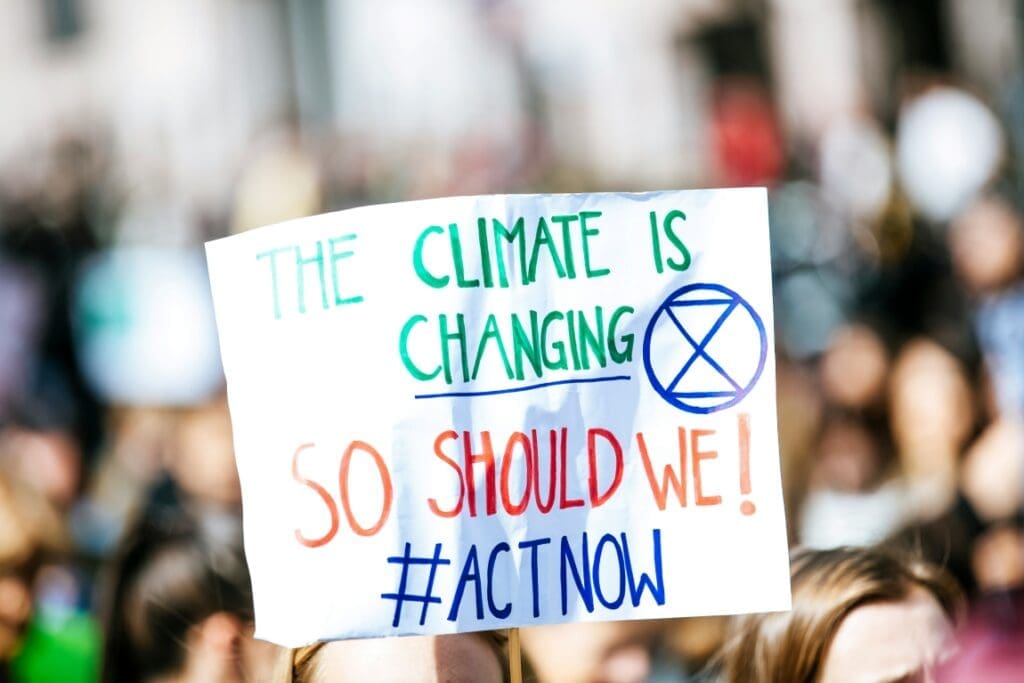 Image: person holding The Climate is Changing signage