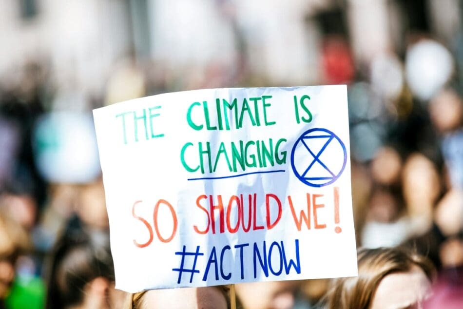 Image: person holding The Climate is Changing signage