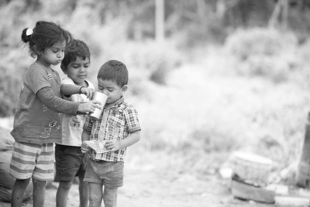 Grayscale Photo of Kids Helping a Child Drink from a Cup (climate effects - drought - heat)