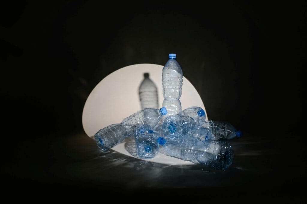 Image: A spotlight cast on plastic bottles on black background (s. plastic pollution)