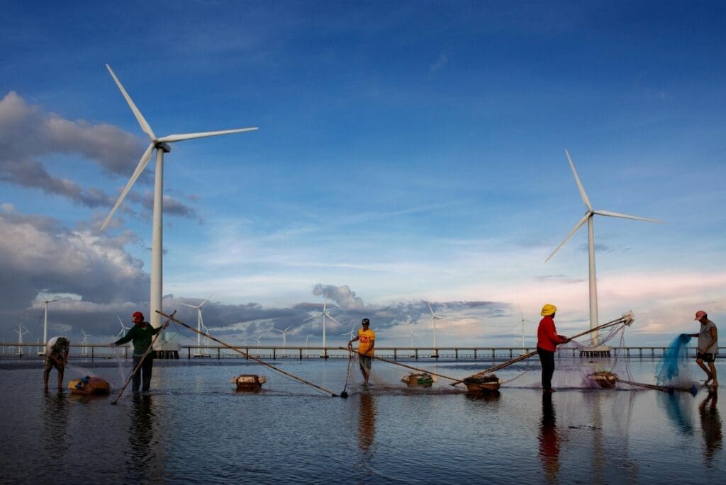 Leading academics call for extending and reframing Sustainable Development Goals Image: Fisherman working near wind turbines
