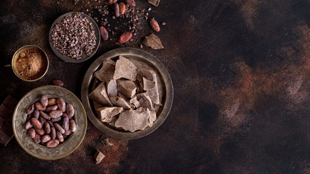 Image: Flat lay of chocolate chunks on plate with cocoa beans and powder and copy