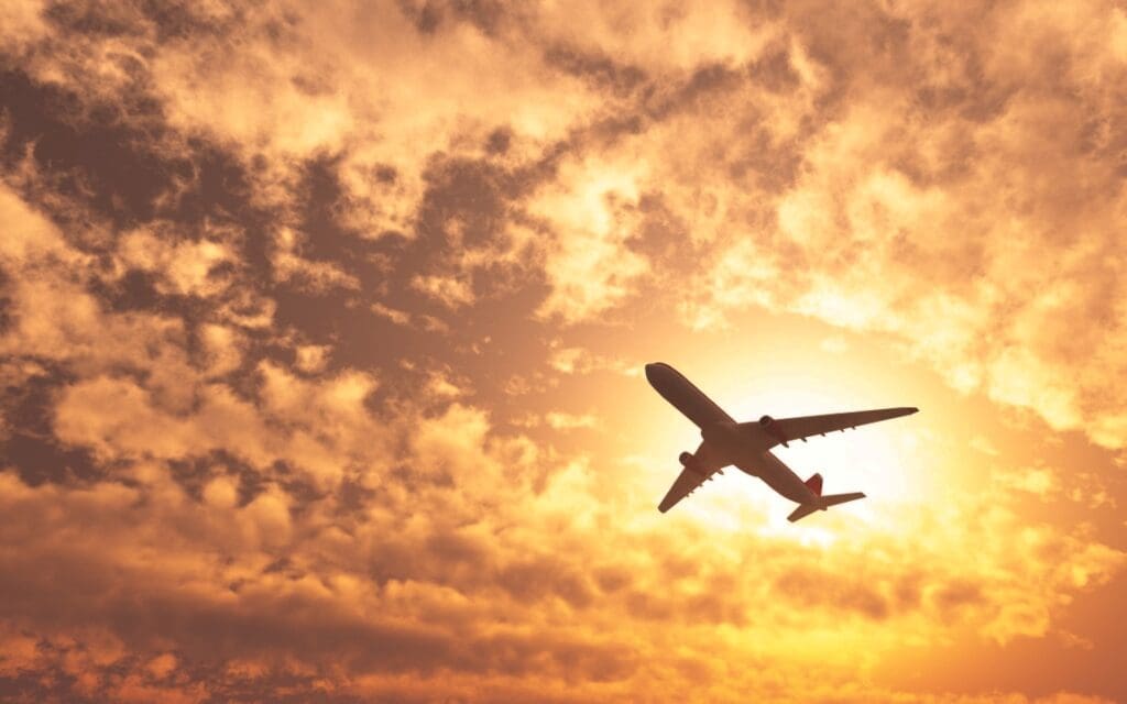 Image: Plane passing by the sun on a cloudy day (s. aviation, greenwashing, pollution)