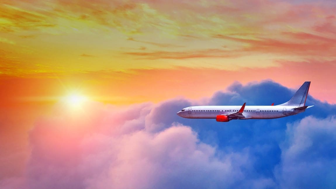 Image: Airplane flying above clouds in sunset light