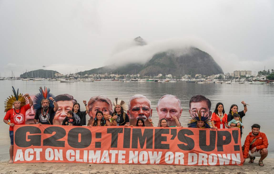 Image: Activists with a banner; background: Images of leaders from rich and polluting countries