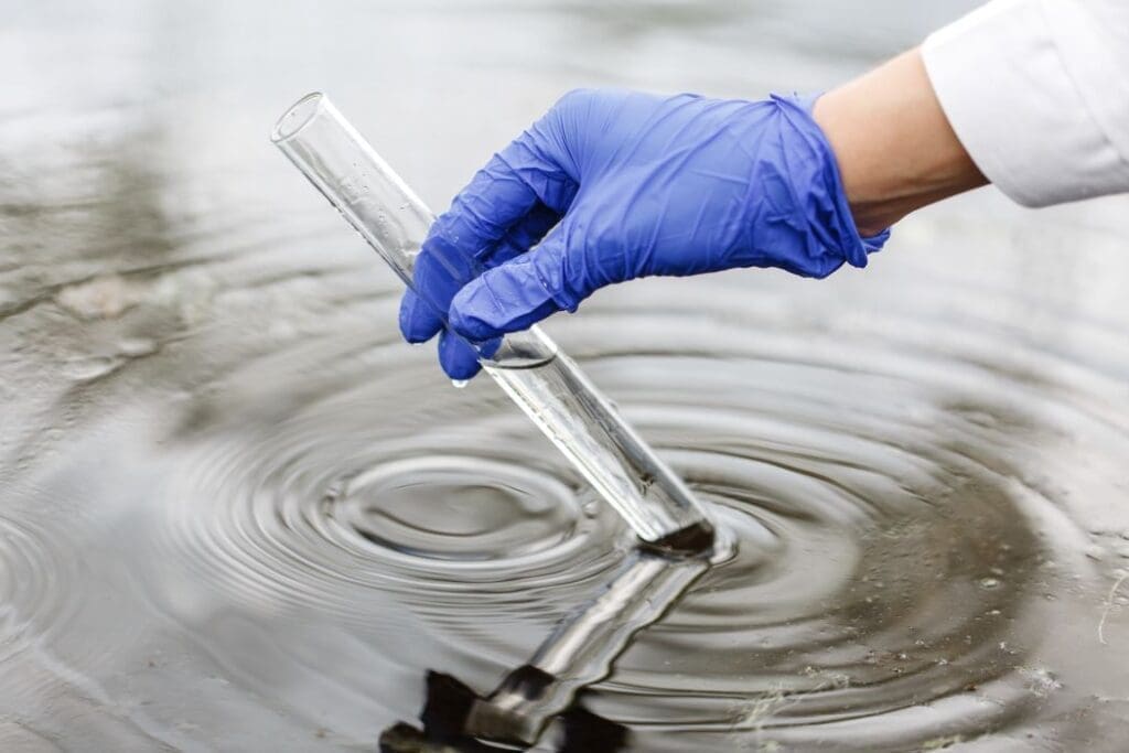 Image: Researcher holds a test tube with water in a hand in blue glove (s. PFAS, forever chemicals, cancer)