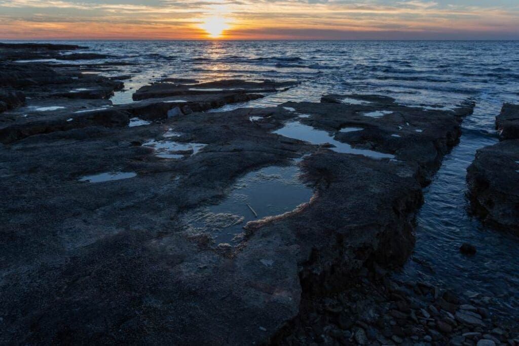 Image: Sun setting at the shore with rock formations (s. ocean evaporation, temperature)