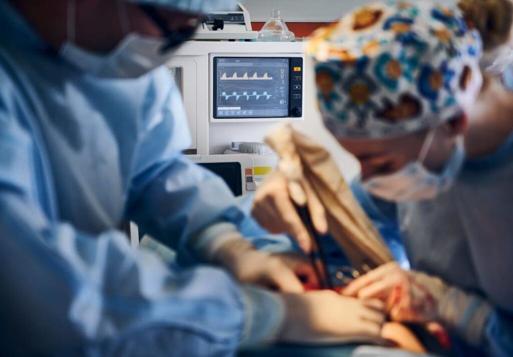 Image: Doctors doing plastic surgery in operating room with patient monitor (s. greener anesthesia)