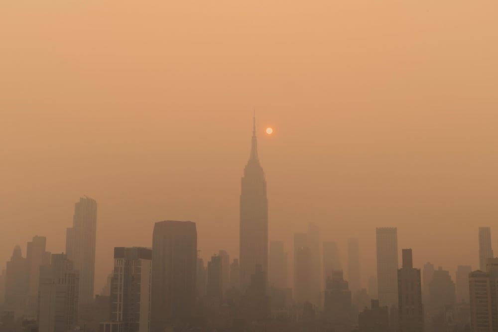 Image: Foggy city skyline with the sun in the distance (photo of New York, wildfire, canada, air pollution)