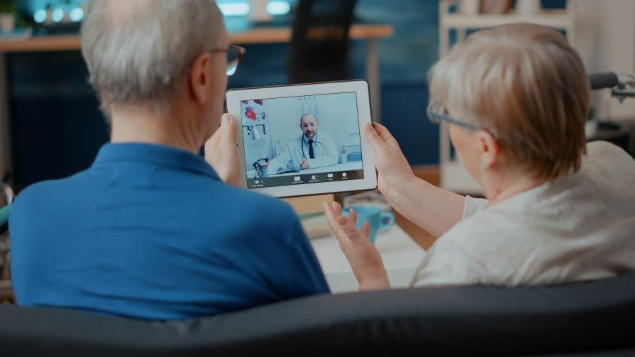 Image: Senior couple attending online meeting with doctor on digital tablet