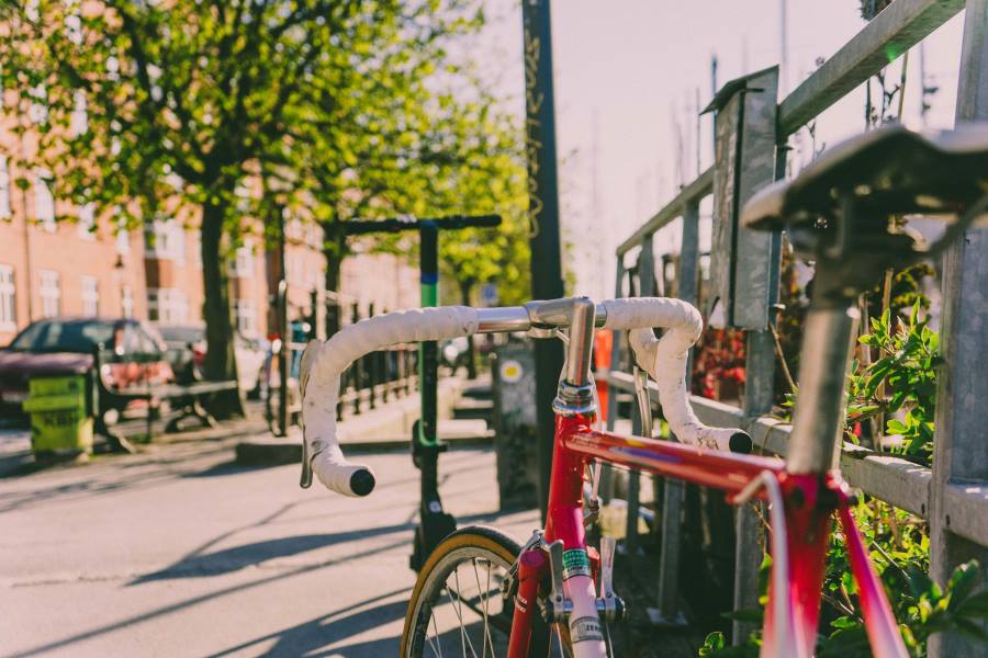 Image: red and white road bike parked near fence (s.Copenhagen to offer giveaways to eco-friendly tourists)