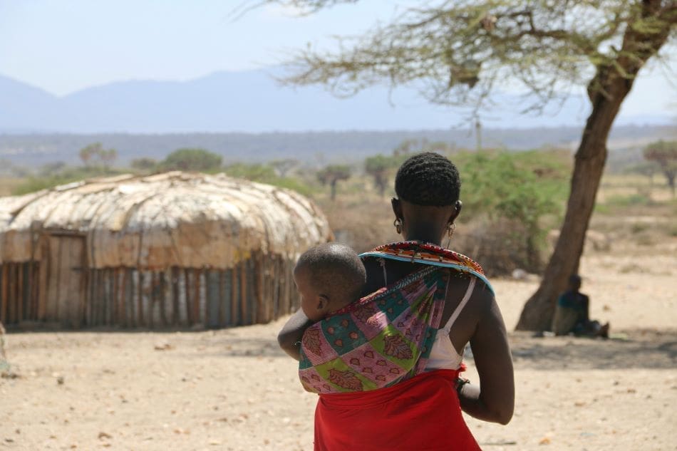 Climate change deepens health risks for young adolescents in Kenya Image: a woman carrying a child on her back