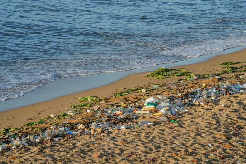 Image: A beach covered in lots of trash next to the ocean (s. plastic pollution, environment)
