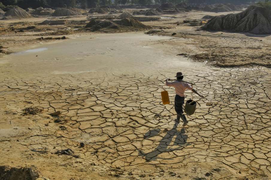Image: Man carrying water on cracked dry land in Myanmar