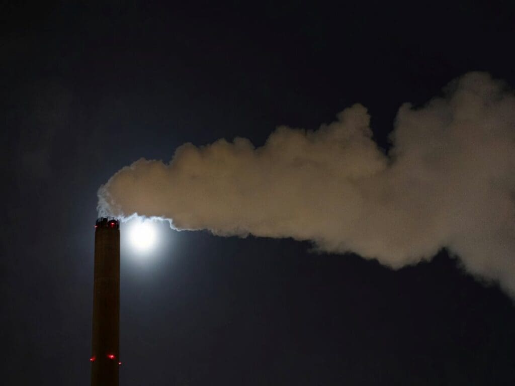 Image: a smokestack emits from a chimney at night