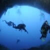 Image: a group of divers swimming in a cave