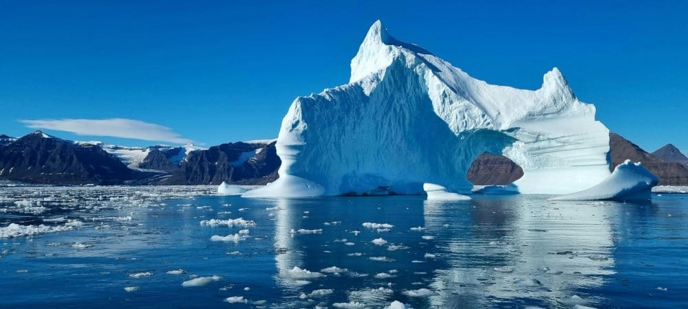 Image: Iceberg on body of water under blue sky