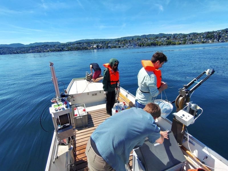 Image: UZH researchers conducting microbial monitoring on Lake Zurich (s. adaptive evolution, soil bacteria)