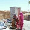Image: Women standing outdoors in a sun-exposed rural area in Sindh, Pakistan, with dry ground and bright midday light