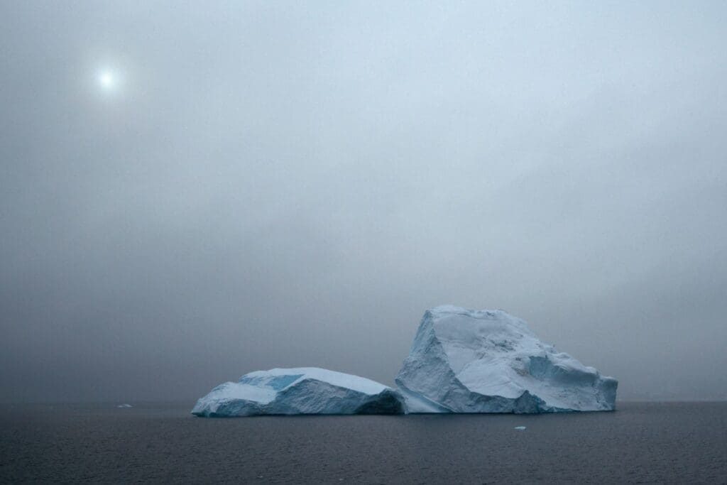 Image: icebergs float in a foggy ocean under sun (s. dimmed sunlight)