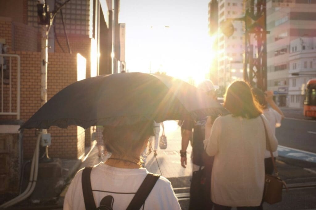 Image: woman in white shirt holding umbrella in a sunny day
