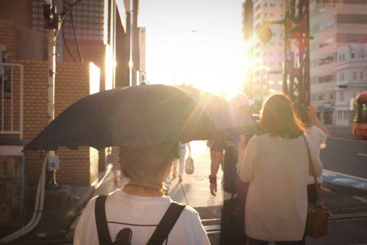 Image: woman in white shirt holding umbrella in a sunny day