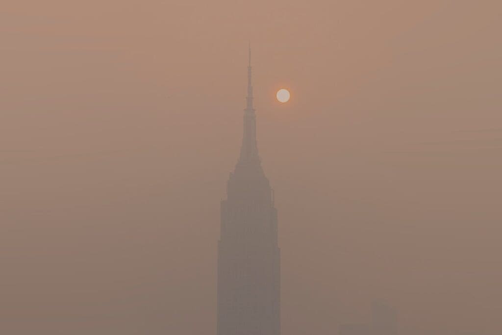 Hazardous Canadian wildfire smoke choking millions in US Image: a foggy skyline with a tall building in the distance