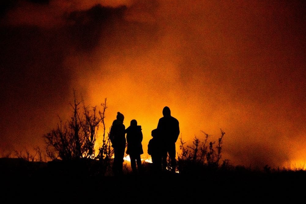 France and Spain battle 'unpredictable' wildfires as 300,000 evacuated Image: family watching a wildfire in the distance